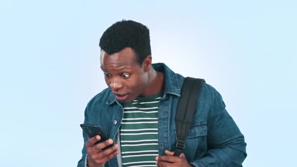 Uomo africano, telefono e notizie a sorpresa in studio con sfondo blu sorridente, felice e beffardo. Ragazzo nero, annuncio e notifica sui social media, tecnologia ed eccitato da un allarme positivo. - Filmati, video