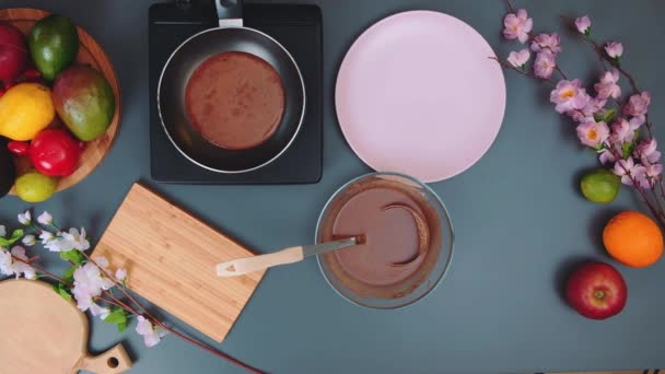 Top kilátás sült csokoládé palacsinta serpenyőben. A konyhaasztal tetején. Főzés a konyhában. - Felvétel, videó