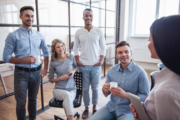 Hermosa gente de negocios están hablando, utilizando gadgets y sonriendo durante el descanso de café en la oficina
 - Foto, imagen