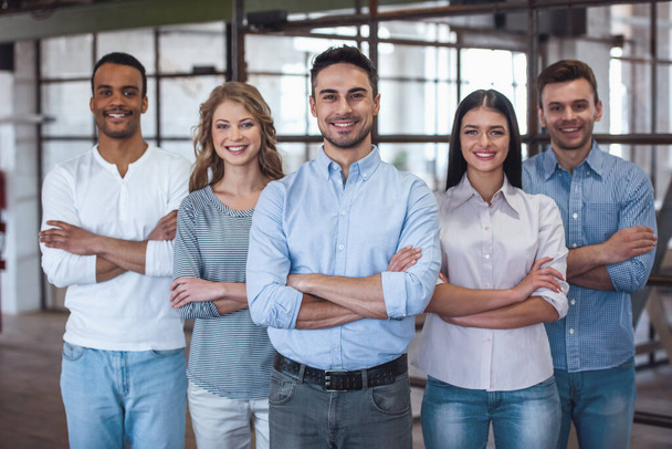 Успішна бізнес команда дивиться на камеру і посміхається, стоячи з перехрещеними руками в офісі
 - Фото, зображення