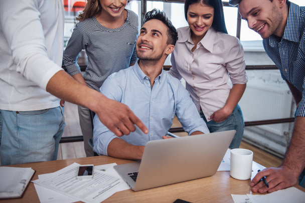 Schöne Geschäftsleute benutzen einen Laptop, unterhalten sich und lächeln während der Konferenz im Büro - Foto, Bild