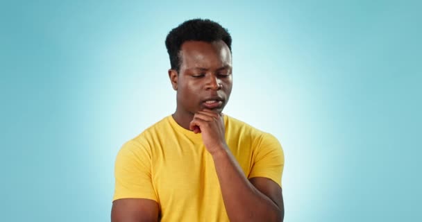 Thinking, stress and black man with solution, confused and questions on a blue studio background. African person, doubt and model with brainstorming, emoji and anxiety with choice, idea and decision. - Footage, Video