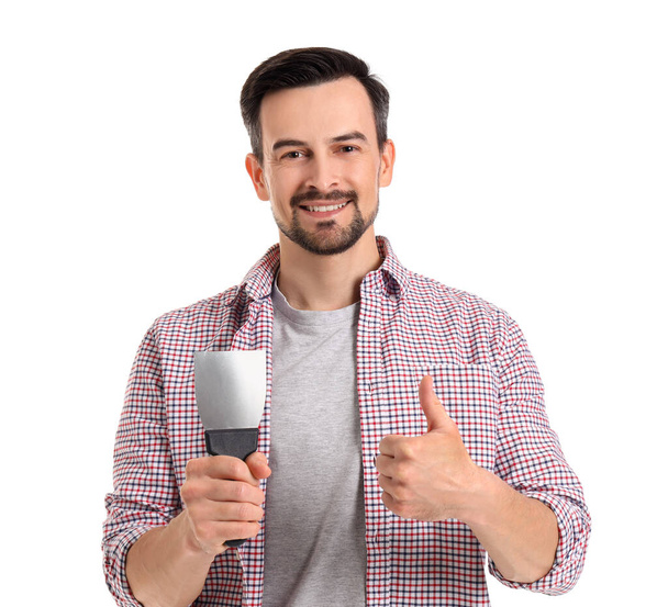 Young man with putty knife showing thumb-up on white background - Photo, Image