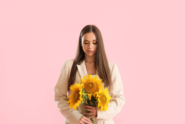 Young woman with bouquet of beautiful sunflowers on pink background - Photo, Image