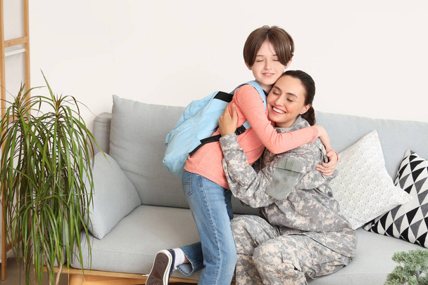 Militaire moeder knuffelen en het maken van haar zoontje klaar voor school in de woonkamer - Foto, afbeelding