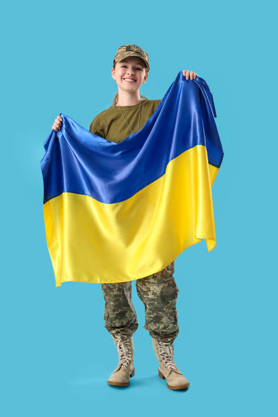 Young female soldier with flag of Ukraine on light blue background - Photo, Image