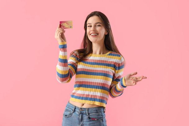 Молода жінка з кредитною карткою на рожевому фоні - Фото, зображення