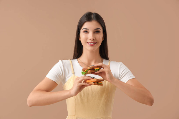 Mujer joven con sabrosos sándwiches en el fondo de color - Foto, imagen