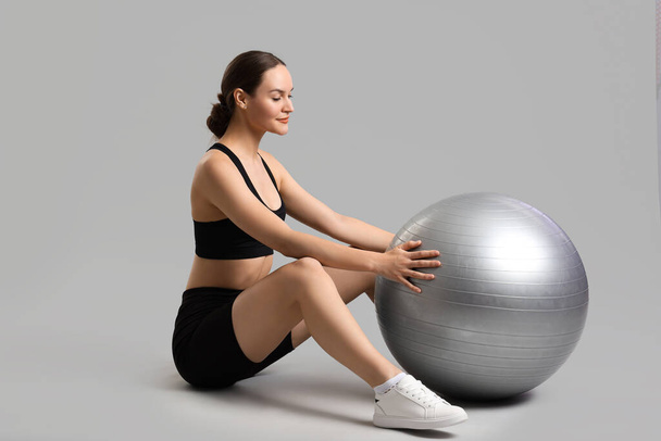 Sporty young woman with fitball on light background - Foto, immagini