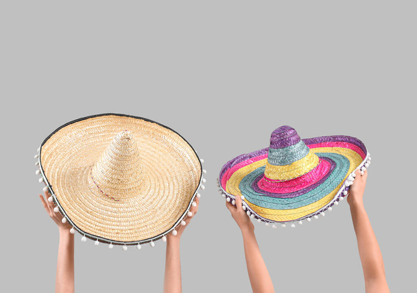 Gri arkaplanda sombreroları tutan kadın eller - Fotoğraf, Görsel