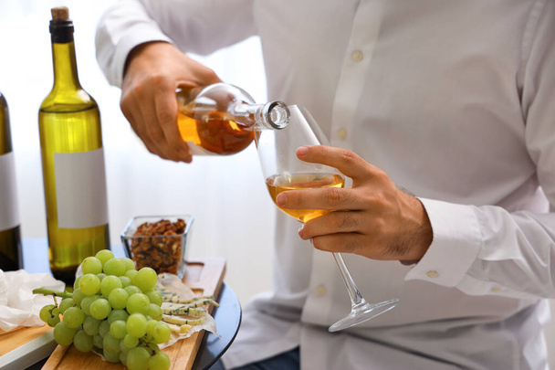 Νεαρός σομελιέ ρίχνει κρασί σε ποτήρι στην κουζίνα, κοντινό πλάνο - Φωτογραφία, εικόνα