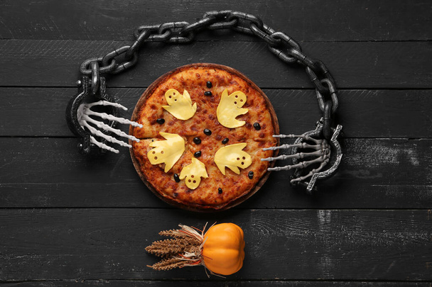 Deska ze smaczną pizzą i dekoracjami na Halloween party na czarnym drewnianym tle - Zdjęcie, obraz
