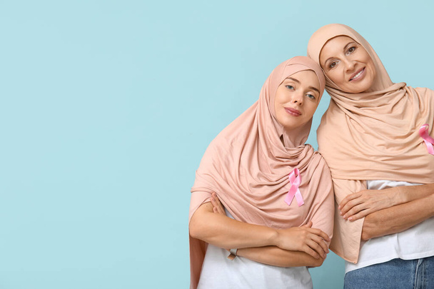Mavi arka planda pembe kurdeleli Müslüman kadınlar. Göğüs kanseri farkındalığı konsepti - Fotoğraf, Görsel