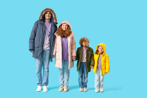 Happy family in puffer jackets on blue background - Photo, Image