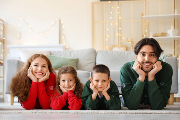 自宅の床に横たわる暖かいセーターで幸せな家族 - 写真・画像