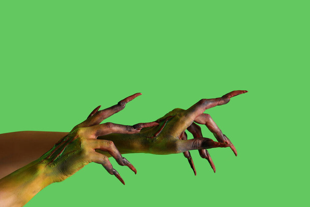 Руки відьми з кігтями на зеленому тлі. святкування Хеллоуїна - Фото, зображення
