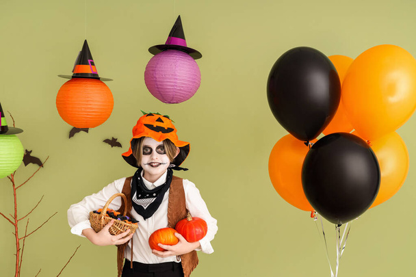 Menino vestido para o Halloween com doces e balões perto da parede verde - Foto, Imagem
