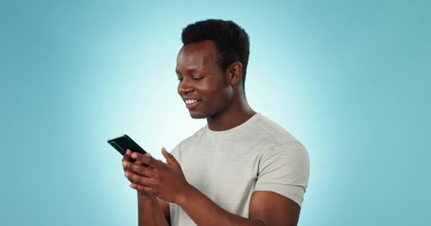 Hombre, conversación y sonrisa para llamada telefónica en el estudio por fondo azul para la comunicación, hola y chat. Persona negra feliz, teléfono inteligente y mensajes de texto sobre la tecnología, riendo y hablar para conectar. - Imágenes, Vídeo