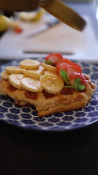Cozinhe derramando chantilly em waffle com pedaços de banana e morango. Conceito Brunch - Filmagem, Vídeo