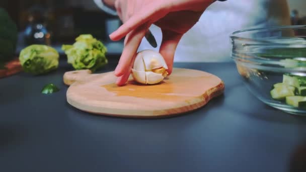 Mulher esmaga um ovo com uma faca em uma tábua de corte. Um plano de perto da mesa. Cozinhar na cozinha. - Filmagem, Vídeo