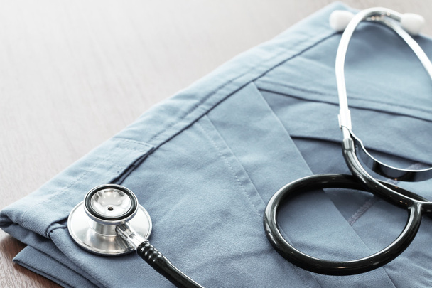 Stetoscopio con cappotto medico blu su tavolo di legno con D superficiale
 - Foto, immagini