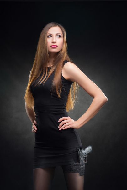 girl in a black dress holding a gun - Fotó, kép