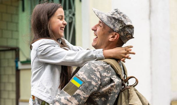 Солдат в українській військовій формі обіймає свою дочку. Сімейна зустріч. - Фото, зображення