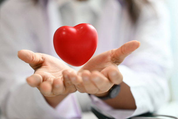 Красное сердце плавает над открытыми руками. Медицинская, кардиологическая, медицинская и благотворительная концепция. - Фото, изображение
