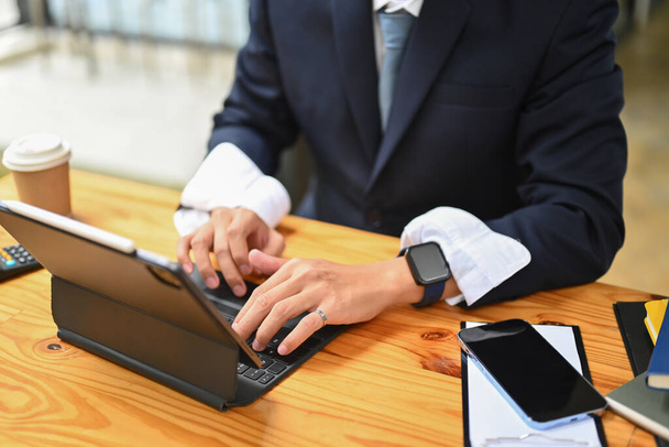 Inversor masculino en traje negro usando tableta digital, analizando datos de marketing, estadísticas en el lugar de trabajo. - Foto, Imagen