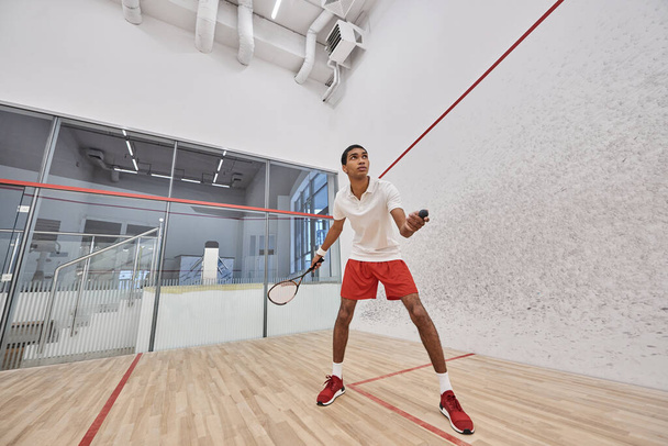 fit african american sportsman holding squash ball and racquet while playing game inside of court - Foto, Bild
