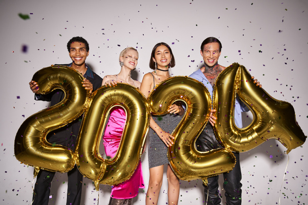 multiethnic friends holding balloons with 2024 numbers near falling confetti, New Year party fun - Foto, Imagem