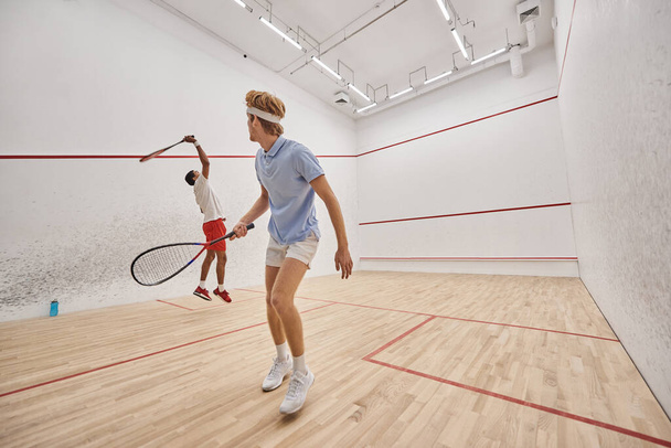 interracial men in sportswear playing squash together inside of court, fitness and motivation - Fotografie, Obrázek