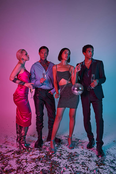 τέσσερις πολυπολιτισμικούς φίλους κρατώντας ποτήρια σαμπάνιας και ντίσκο μπάλα σε μωβ ροζ φόντο - Φωτογραφία, εικόνα