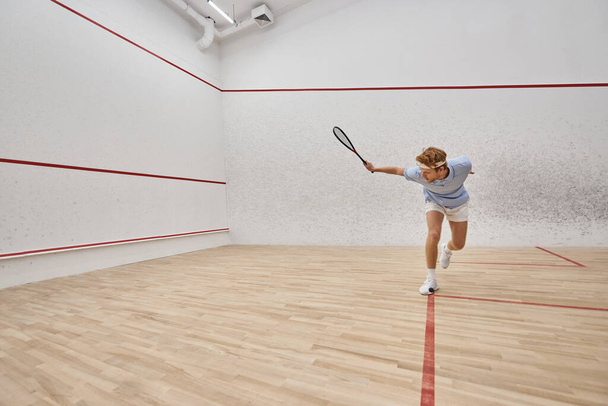 young and active redhead man in sportswear playing squash inside of court, challenge and motivation - Foto, Bild