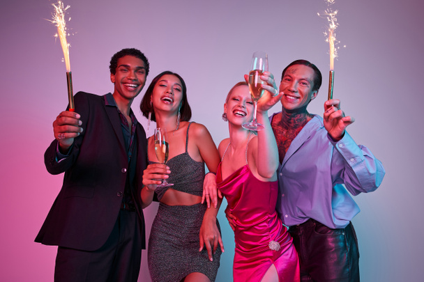 Merry Christmas and Happy New Year, joyous multiethnic friends holding sparklers and champagne - Photo, Image