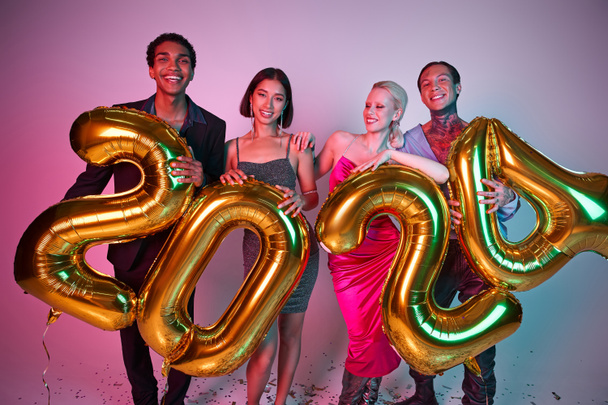 Vrolijk kerstfeest en gelukkig nieuwjaar, positieve interraciale vrienden houden ballonnen met 2024 nummers - Foto, afbeelding