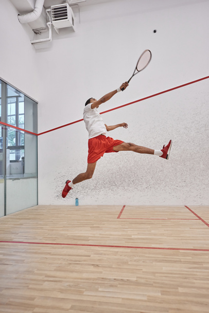 motion shot, active african american player holding racquet while jumping and playing squash - Photo, Image