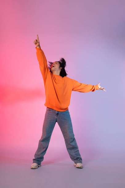 Image of a young Asian person dancing on a neon colored background - Foto, imagen