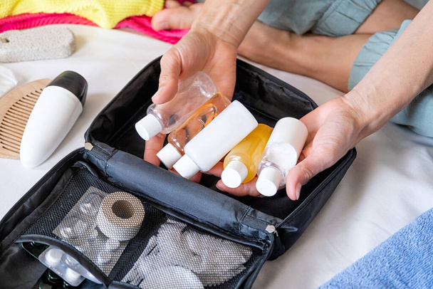 Kit cosmetici da viaggio con flaconi, pillole e cosmetici sul letto, vista dall'alto - Foto, immagini