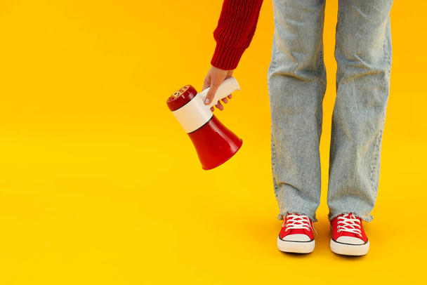 Legs in multi-colored sneakers with a horn on a yellow background. - Photo, Image