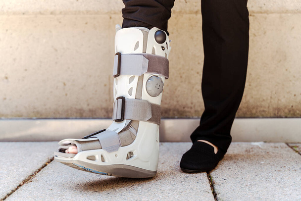 Detailní záběr osoby se zlomenými chodidly v šedé chrání plastovou botu před poraněním kotníku. Koncept traumatu a zotavení - Fotografie, Obrázek