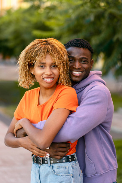 Porträt eines schönen glücklichen Paares, das sich umarmt und in die Kamera blickt, die zusammen im Park steht. Beziehung, Datumskonzept  - Foto, Bild