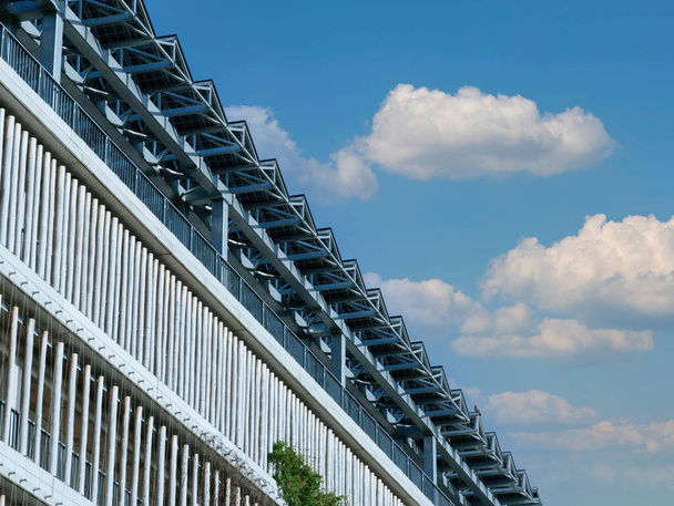 Ηλιακές μπαταρίες είναι περίοπτη εγκατασταθεί στην οροφή ενός σύγχρονου κτιρίου στάθμευσης, πλαισιώνεται από ένα φόντο ενός έντονα καθαρό γαλάζιο ουρανό - Φωτογραφία, εικόνα