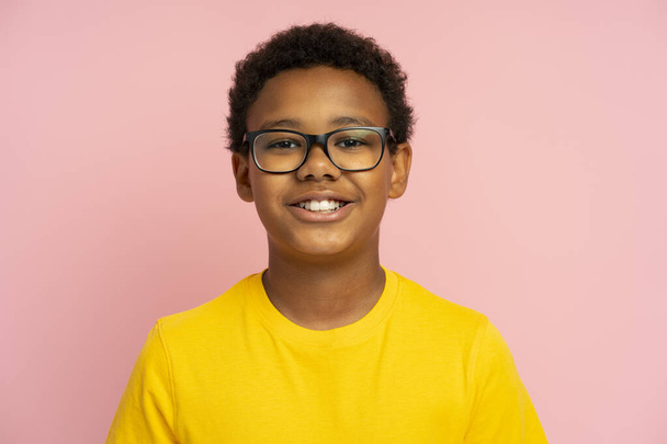 Χαμογελαστό σχολιαρόπαιδο με στυλάτα γυαλιά, απομονωμένο σε ροζ φόντο. Εκπαιδευτική έννοια - Φωτογραφία, εικόνα