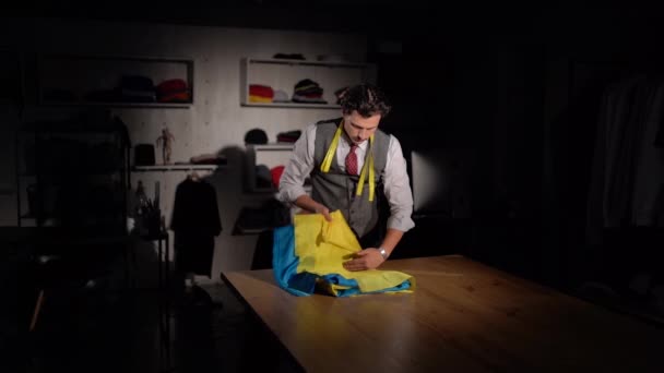 Kiev, Ucrânia - outubro de 2023: Um alfaiate costura uma bandeira ucraniana em um estúdio de costura. Uma máquina de costura costura costura a bandeira da Ucrânia. Costurar tecido azul e amarelo. - Filmagem, Vídeo