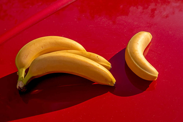 keltaiset kypsät banaanit punaisella taustalla - Valokuva, kuva