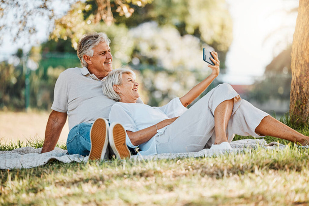 Picnic, selfie and senior couple with love, relax and connection with social media, retirement and marriage. Romance, outdoor and old woman with elderly man, digital app and relationship with bonding. - Photo, Image