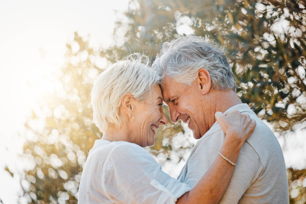 Senior couple, forehead or hug in nature garden for love, support or bonding retirement trust. Woman smile, lens flare or elderly man in embrace for relationship, connection and together in backyard. - Photo, Image