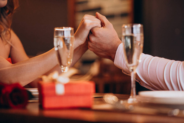 Пара держащихся за руки на валентинках вечером в ресторане - Фото, изображение
