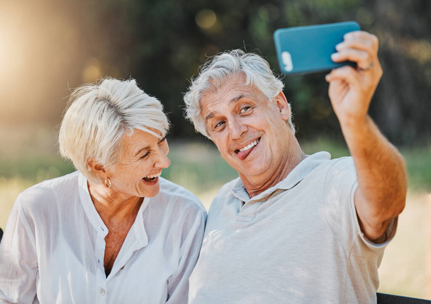 Senioren paar, tong en selfie in de openlucht natuur tuin voor liefde geheugen, verbinding en pensioen emoji. Oudere man, grappig gezicht en lachende vrouw voor social media fotografie en profielfoto. - Foto, afbeelding